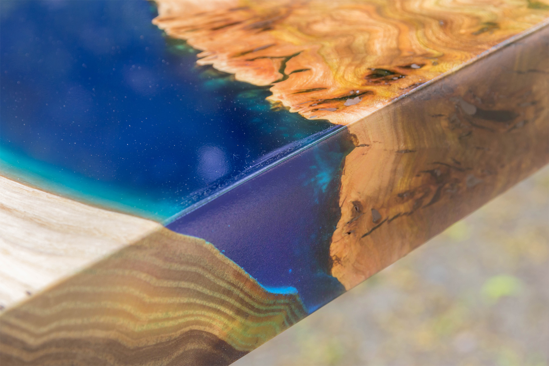 The edge of a beautiful blue live edge epoxy table